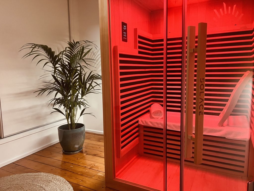 Inside the infrared sauna with the heaters glowing red and a towel on the bench